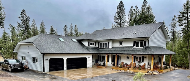 view of front facade featuring covered porch, roof with shingles, driveway, and an attached garage