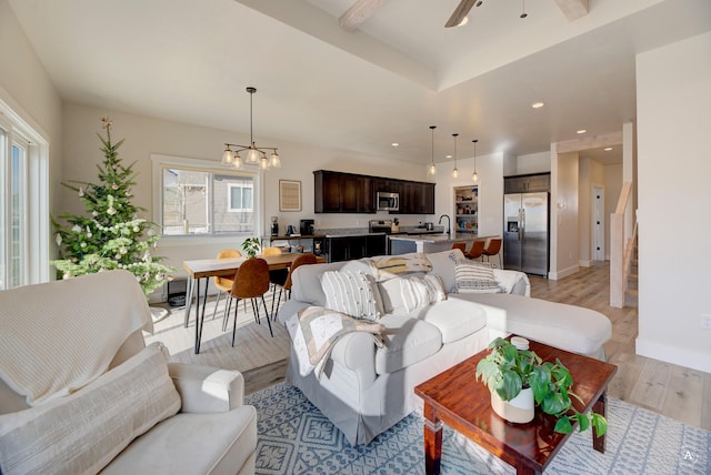 living room with light wood finished floors, recessed lighting, baseboards, stairs, and ceiling fan with notable chandelier