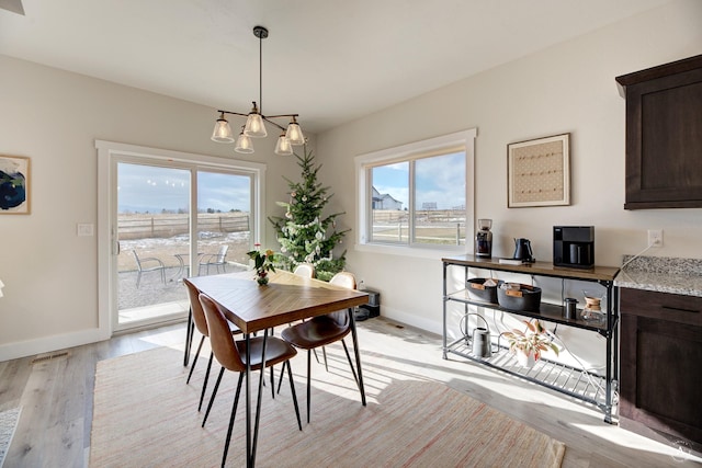 dining area featuring light wood-style floors, visible vents, and baseboards