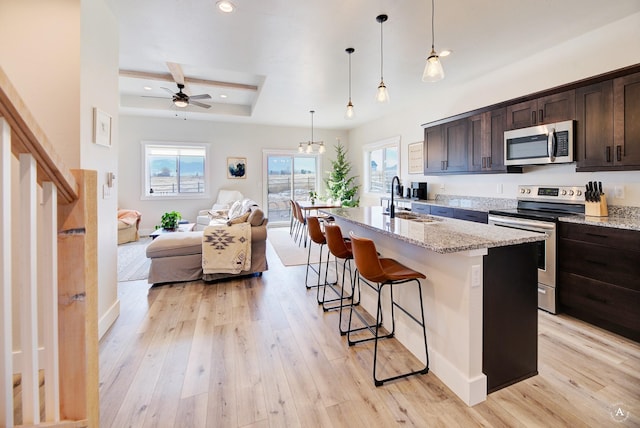 kitchen featuring dark brown cabinets, a center island with sink, stainless steel appliances, and a sink