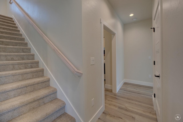 staircase with baseboards, wood finished floors, and recessed lighting