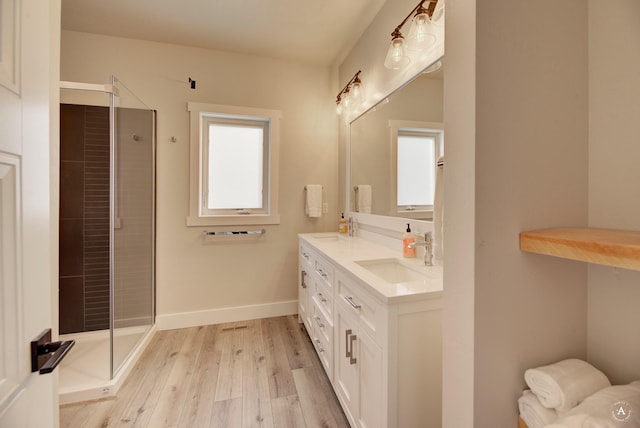 full bathroom featuring a shower stall, baseboards, a sink, and wood finished floors