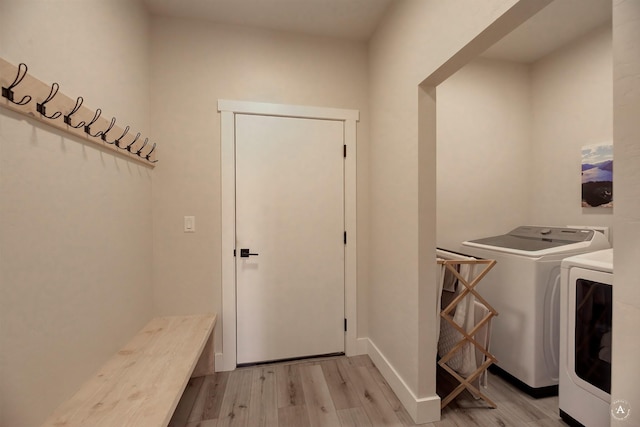 clothes washing area with laundry area, baseboards, light wood-style floors, and washer and dryer