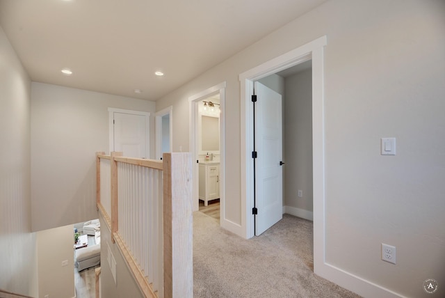 corridor featuring an upstairs landing, recessed lighting, light colored carpet, and baseboards