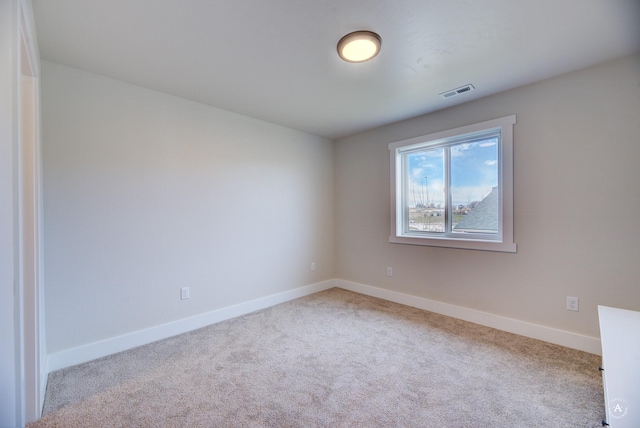 empty room featuring baseboards, visible vents, and light colored carpet