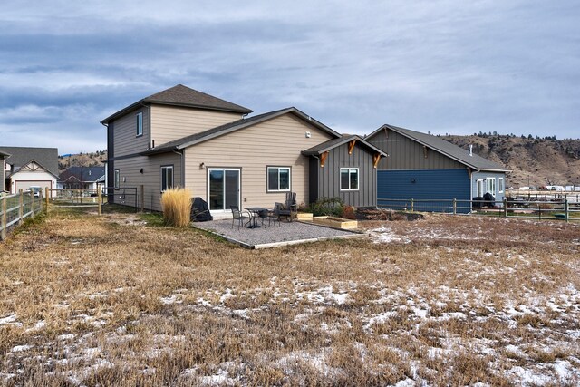 snow covered house with board and batten siding, a patio area, and a fenced backyard