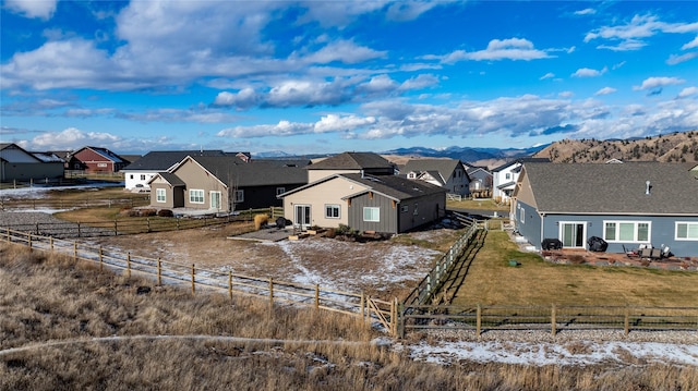 view of front of home with a residential view, a rural view, fence, and a mountain view