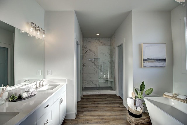 full bathroom featuring double vanity, a marble finish shower, a soaking tub, wood finished floors, and a sink