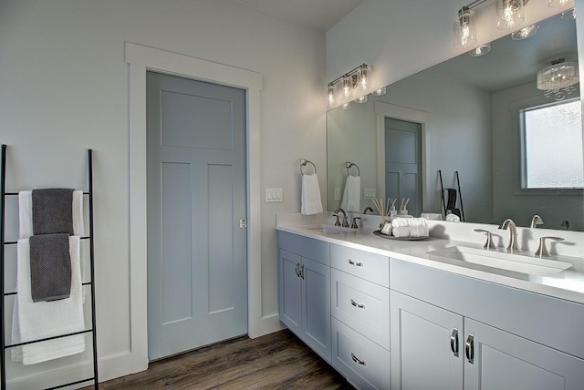 full bath featuring double vanity, wood finished floors, and a sink