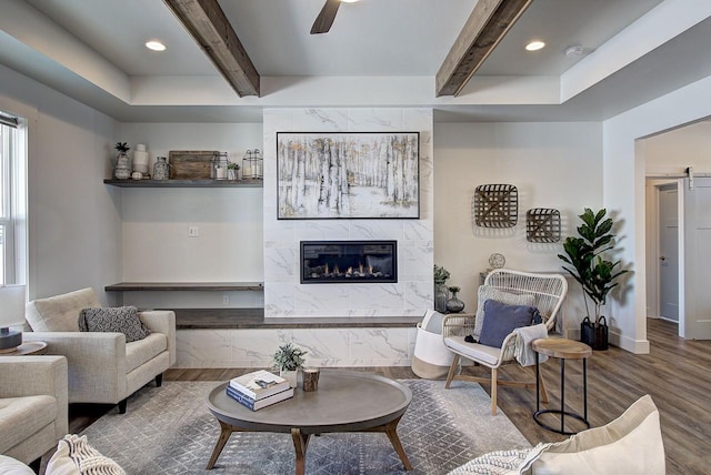 living room with a barn door, beamed ceiling, a fireplace, and wood finished floors