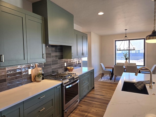 kitchen with a sink, decorative backsplash, light stone countertops, dark wood finished floors, and gas range