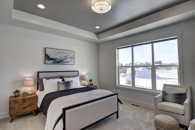 bedroom featuring baseboards, visible vents, a raised ceiling, and light colored carpet