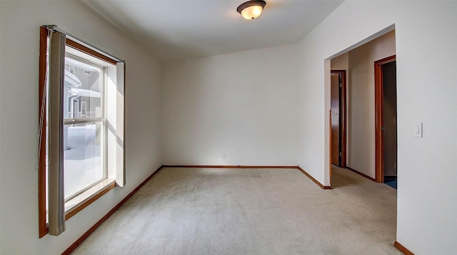 unfurnished room featuring light carpet and baseboards