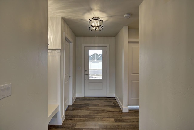 doorway to outside featuring a notable chandelier, dark wood finished floors, and baseboards