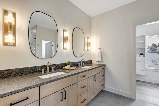 bathroom with double vanity, a sink, and baseboards