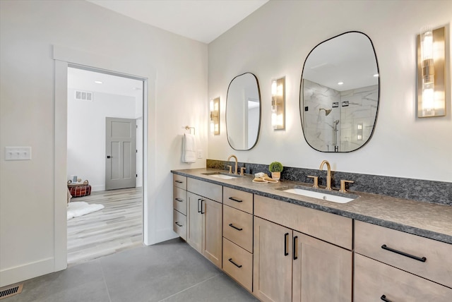 bathroom with visible vents, a sink, a tile shower, and double vanity