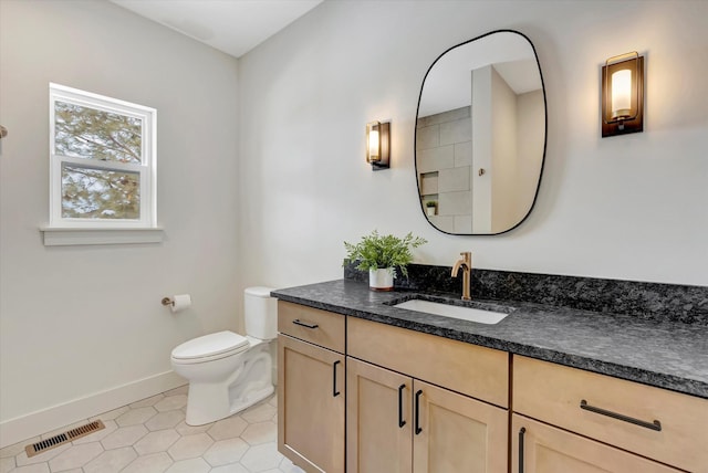 bathroom with toilet, vanity, baseboards, visible vents, and tile patterned floors