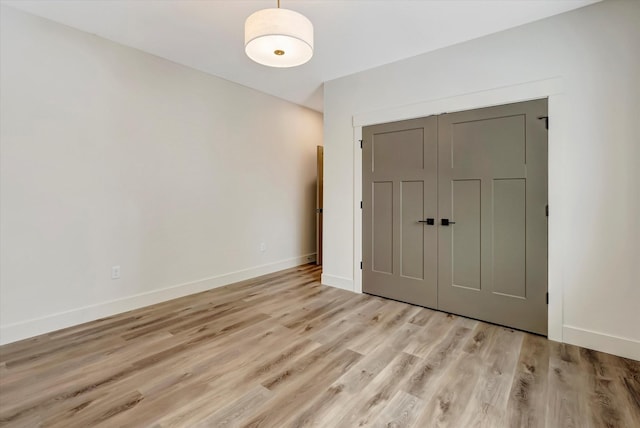 unfurnished bedroom with a closet, light wood-style flooring, and baseboards