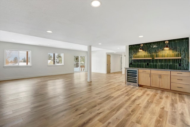 unfurnished living room featuring light wood finished floors, wine cooler, recessed lighting, and wet bar