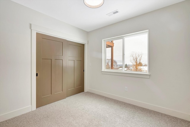 unfurnished bedroom featuring carpet floors, a closet, visible vents, and baseboards