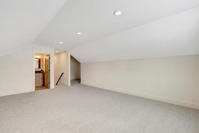 additional living space with recessed lighting, light colored carpet, vaulted ceiling, and baseboards