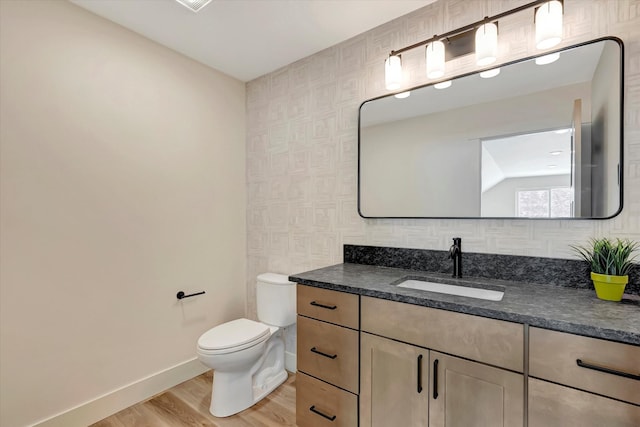 bathroom with toilet, baseboards, wood finished floors, and vanity