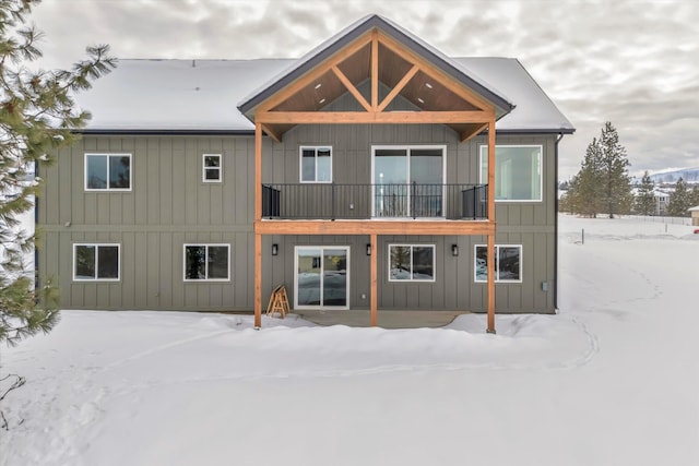 snow covered rear of property with board and batten siding