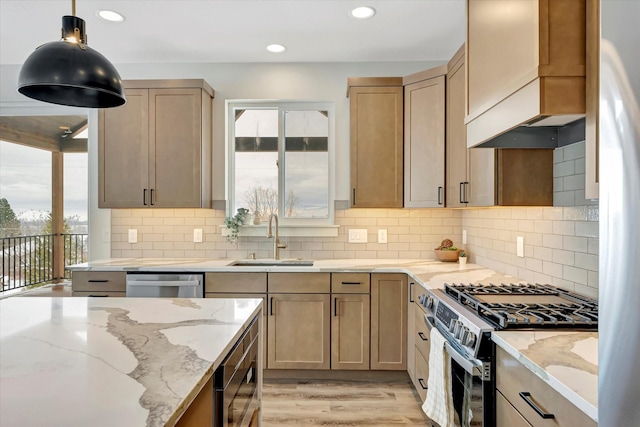 kitchen with custom exhaust hood, stainless steel appliances, light brown cabinetry, pendant lighting, and a sink