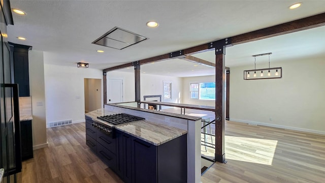 kitchen with light stone counters, visible vents, open floor plan, and beamed ceiling