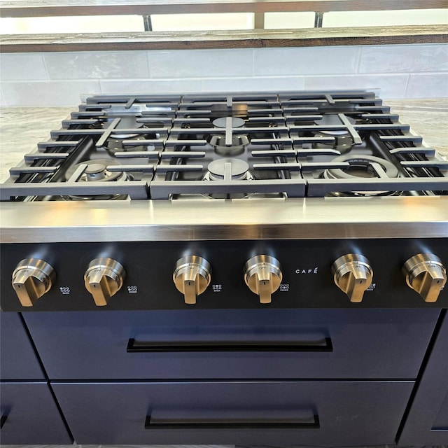 interior details with tasteful backsplash, stainless steel stove, and light countertops