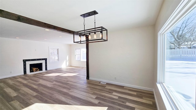 unfurnished living room with beamed ceiling, a brick fireplace, dark wood finished floors, and baseboards