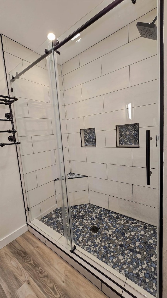 full bath featuring a shower stall and wood finished floors