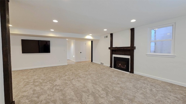 basement with baseboards, a fireplace, visible vents, and light colored carpet