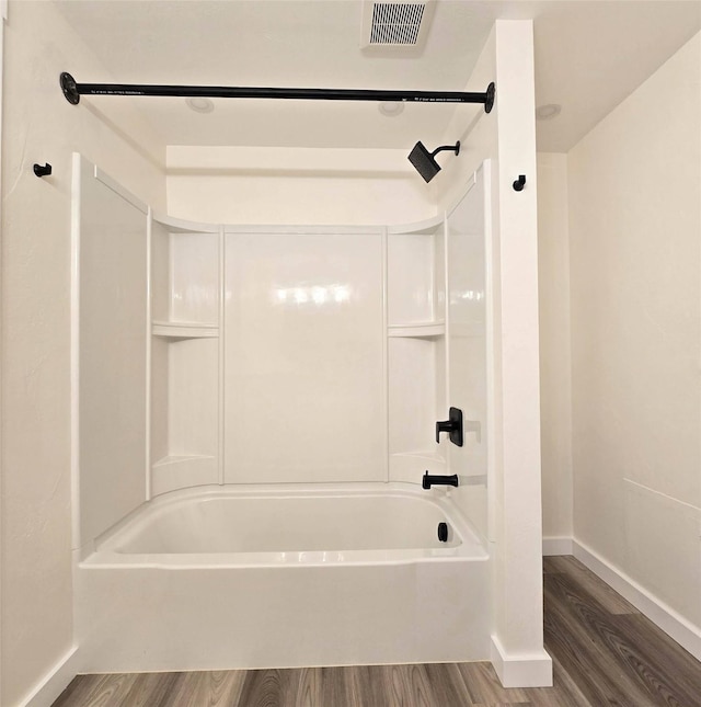 bathroom featuring  shower combination, wood finished floors, visible vents, and baseboards