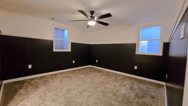 carpeted spare room with a ceiling fan, a wainscoted wall, and visible vents