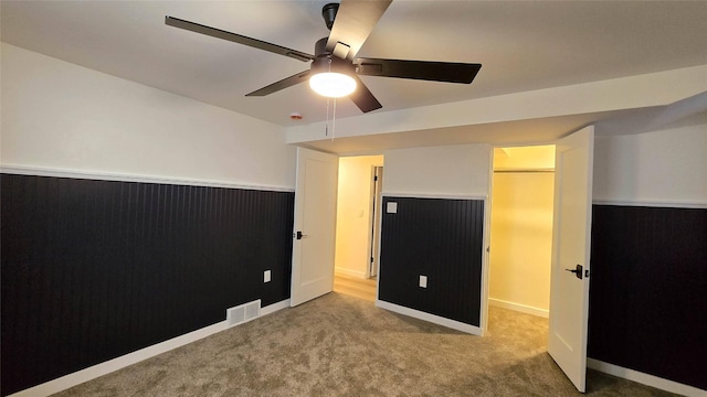 unfurnished bedroom with carpet flooring, visible vents, and a ceiling fan