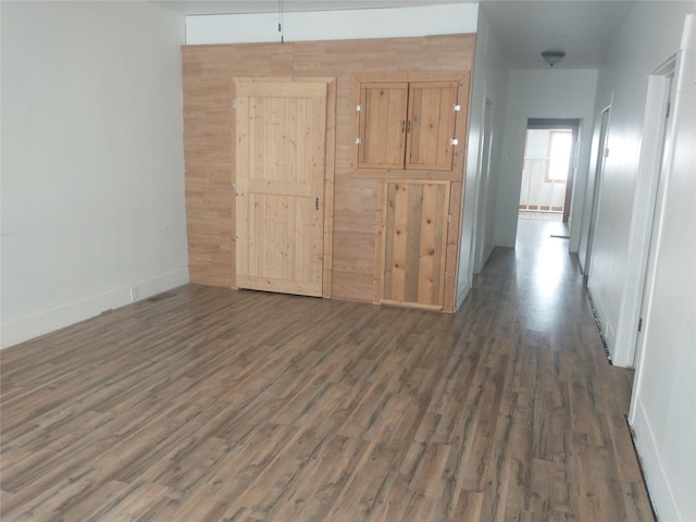 corridor featuring dark wood-style floors and baseboards