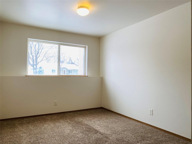 carpeted spare room featuring baseboards