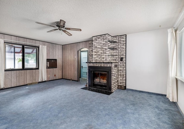 3501 1st Ave S, Great Falls, MT 59401 - unfurnished living room featuring ceiling fan, a textured ceiling, a brick fireplace, wooden walls, and arched walkways
