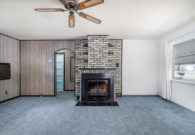 3501 1st Ave S, Great Falls, MT 59401 - unfurnished living room with carpet floors, a textured ceiling, a brick fireplace, ceiling fan, and wood walls