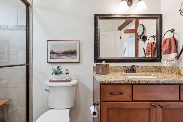 full bath featuring toilet, tiled shower, and vanity