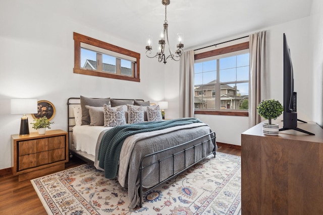 bedroom featuring an inviting chandelier, baseboards, and wood finished floors