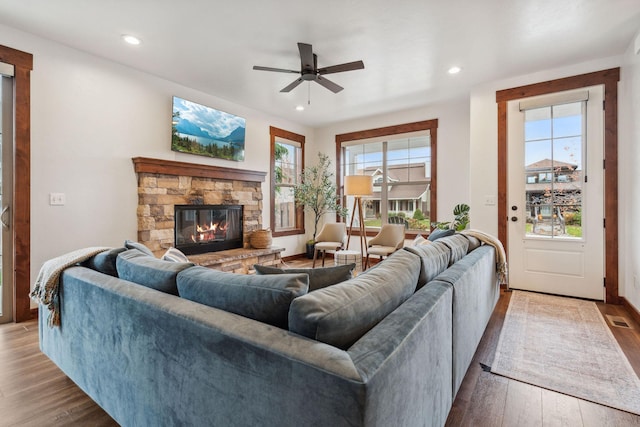 living area with a stone fireplace, wood finished floors, and recessed lighting