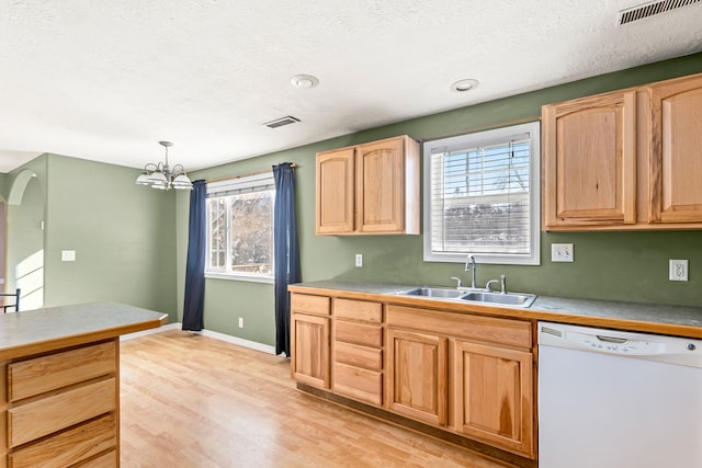 kitchen with white dishwasher, light brown cabinets, a sink, visible vents, and light wood-type flooring