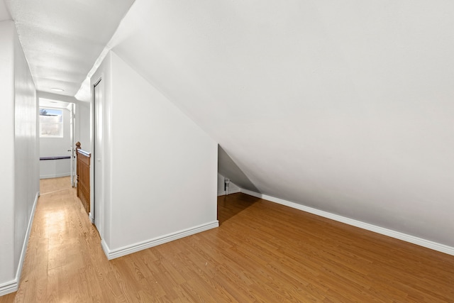 bonus room featuring lofted ceiling, baseboards, and light wood finished floors