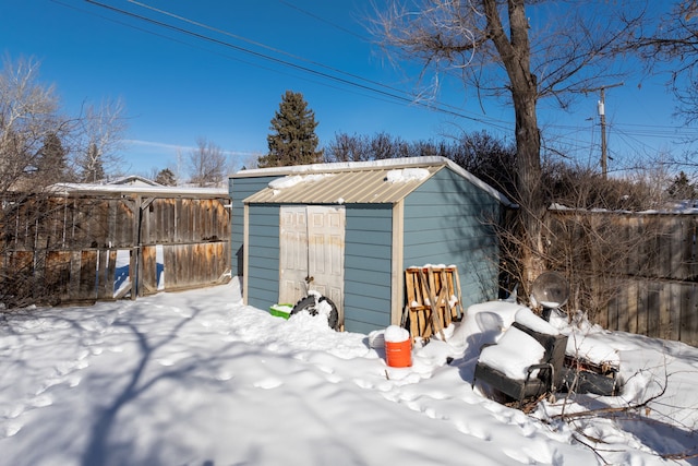 snow covered structure with an outbuilding and a shed