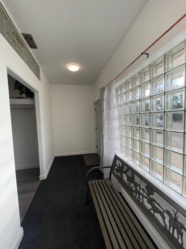 hall featuring baseboards, visible vents, and dark colored carpet