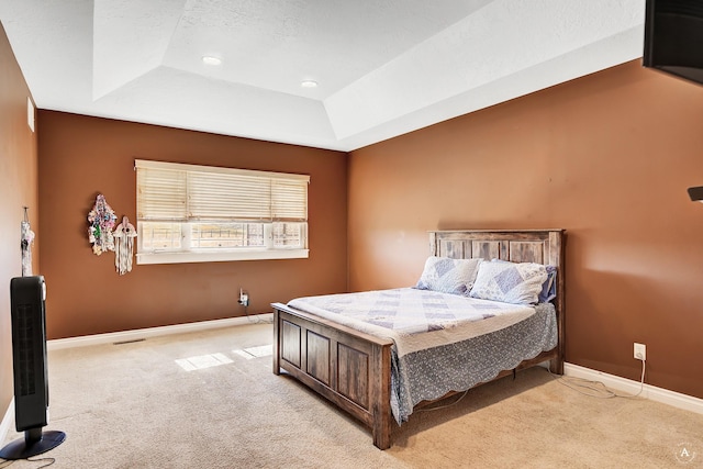 bedroom with light carpet, baseboards, and a tray ceiling