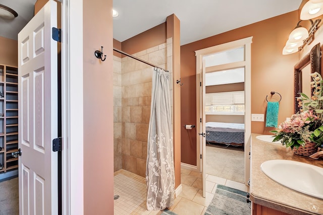 ensuite bathroom featuring double vanity, tile patterned flooring, a shower stall, and a sink