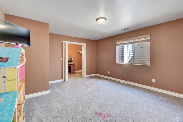 unfurnished bedroom featuring carpet, visible vents, baseboards, and a walk in closet